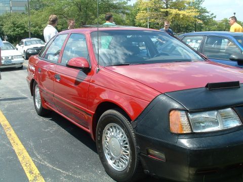 1993 Ford Taurus - Red 1993 Ford Taurus sedan parked in a lot, partially obscured by a car bra.