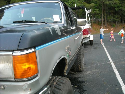 1979 Ford F-150 - A two-tone Ford F-Series truck is parked next to a boat on a trailer, with children in the background.