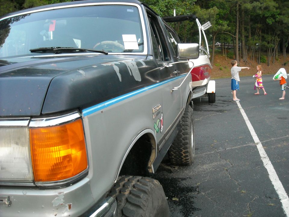 Two-tone gray and dark blue Ford F-Series truck with a boat on a trailer