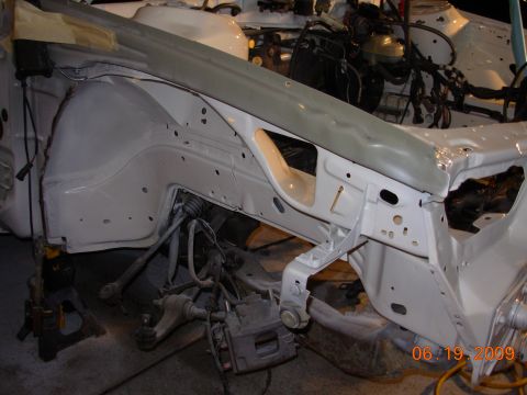 1995 Ford Taurus - The front suspension and wheel well area of a vehicle undergoing restoration, showing exposed mechanical components.