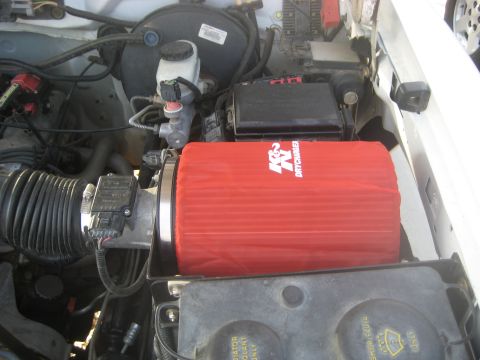 1996 Ford Bronco - Close-up of an engine bay a red K&N Drycharger air filter and associated intake components.