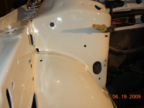 1995 Ford Taurus - Close-up of a vehicle's inner fender well, showing painted metal and some attached components.
