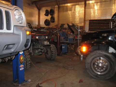 1992 Ford Bronco - A black truck with an illuminated orange turn signal is parked in a garage next to other vehicles.