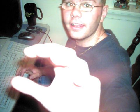 1990 Ford Taurus - A person is captured in a close-up shot while seated at a computer desk, with their hand extended forward.