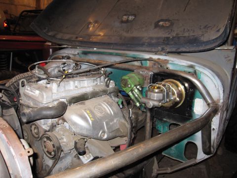 1992 Ford Bronco - The engine bay of a vehicle is shown with custom roll cage tubing and various engine parts.