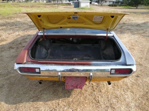 1975 Ford Ranchero - The open trunk of a car reveals its interior storage space, with a chrome bumper and exhaust pipes visible at the rear.