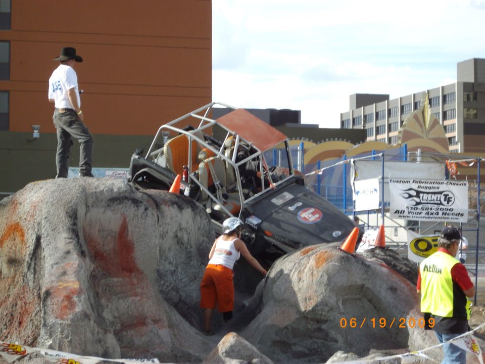 Off-road buggy with roll cage climbing rocks, orange roof, black body