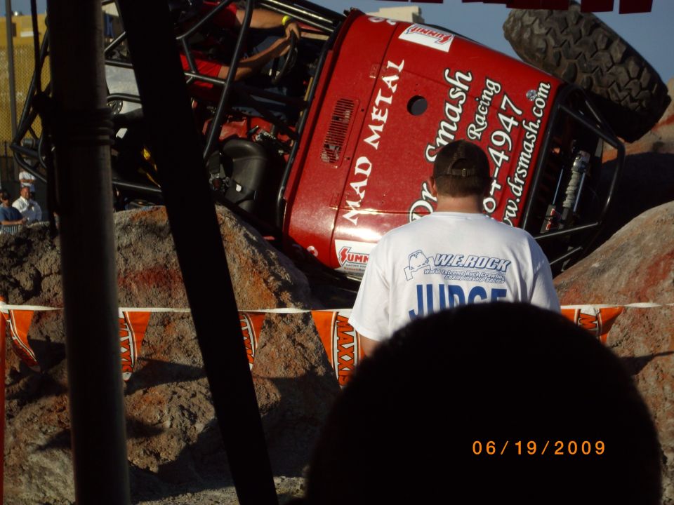 Red off-road vehicle tilted on rocks with "MAD METAL" and "Dr Smash Racing" text