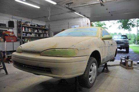 1996 Ford Bronco - A car is being worked on in a garage, with a truck visible in the background.
