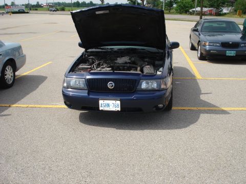 2000 Ford Crown Victoria - Front view of a blue 2000 Ford Crown Victoria with its hood open, revealing the engine compartment.