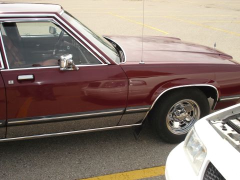 2000 Ford Crown Victoria - A maroon sedan with chrome accents is parked next to a white vehicle in a parking lot.
