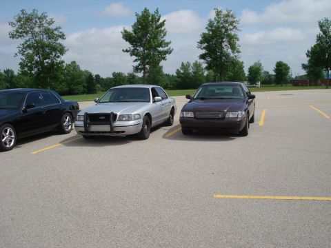 2000 Ford Crown Victoria - Two Ford Crown Victoria police cars are parked in a lot on a sunny day.