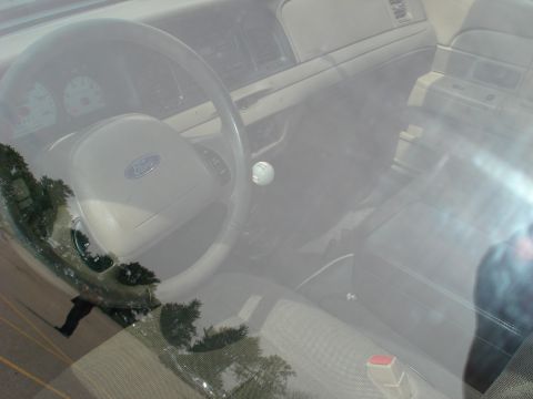 2000 Ford Crown Victoria - The interior of a 2000 Ford Crown Victoria is visible through the windshield, the steering wheel and dashboard.