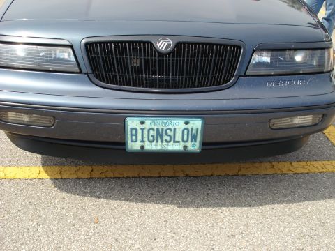 2000 Ford Crown Victoria - The front grille and headlights of a Mercury Grand Marquis are visible, along with its license plate.
