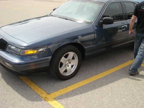 2000 Ford Crown Victoria - A dark blue sedan, likely a 1998 model, is parked in a lot with yellow lines.