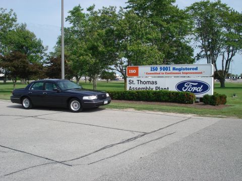 2000 Ford Crown Victoria - A dark sedan is parked in front of the St. Thomas Assembly Plant sign.