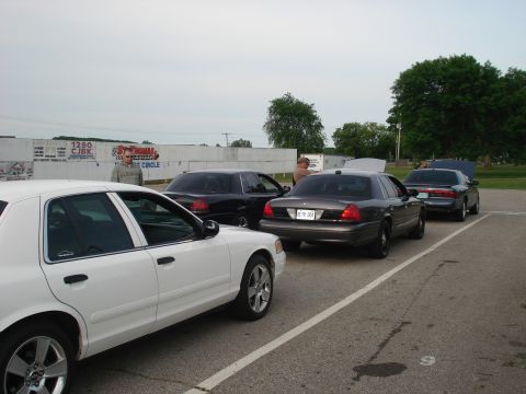 2000 Ford Crown Victoria - Several police cruisers are parked in a lot, with two having their hoods open for inspection.