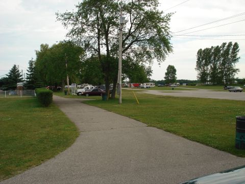 2000 Ford Crown Victoria - A view of a parking area with multiple vehicles, including RVs and cars, surrounded by grass and trees.