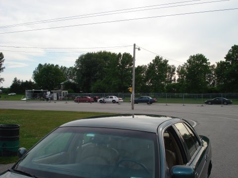 2000 Ford Crown Victoria - A dark green 2000 Ford Crown Victoria is parked in a lot with other vehicles and trees in the background.