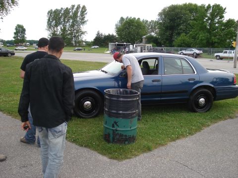 2000 Ford Crown Victoria - A blue 2000 Ford Crown Victoria is parked on grass, with several people gathered around it.