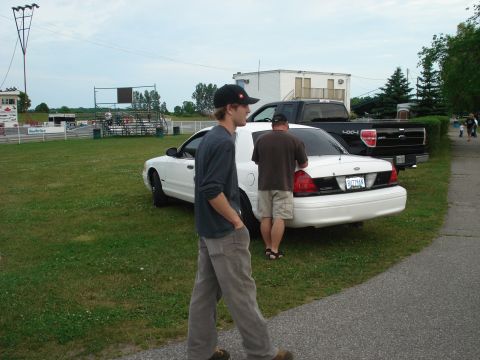 2000 Ford Crown Victoria - A white sedan and a black pickup truck are parked on the grass at what appears to be a race track.
