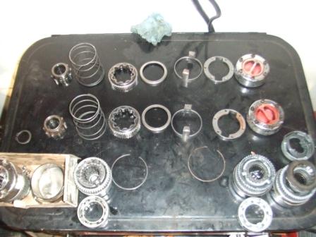 1996 Ford Bronco - Various automotive components are spread across a dark, flat surface, suggesting a repair or assembly process.