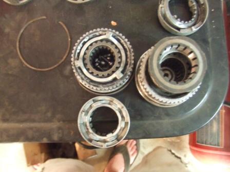 1996 Ford Bronco - Transmission components, including gears and a snap ring, are displayed on a dark workbench.
