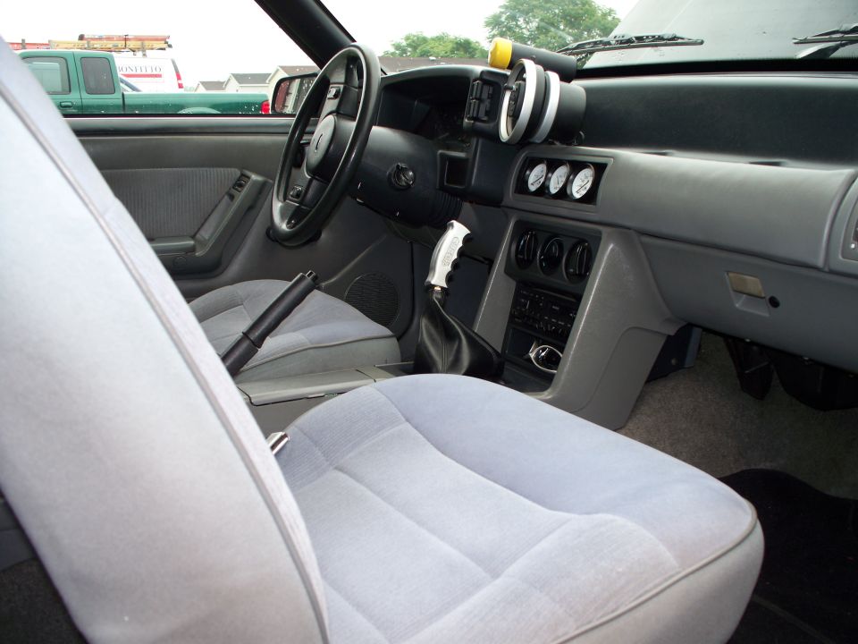car interior with bucket seats, dashboard, steering wheel, and aftermarket gauges