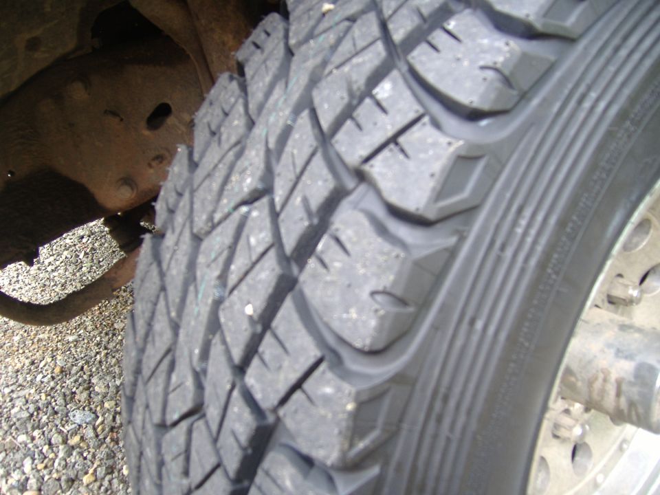 Close-up of new all-terrain tire tread on truck wheel over gravel