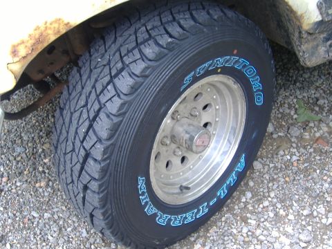 1988 Ford Bronco - Close-up of a new Sumitomo All-Terrain tire with blue-outlined raised white lettering mounted on a polished aluminum eight-hole slotted whe…
