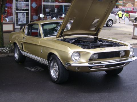 1970 Ford Ranchero - A gold 1968 Ford Mustang GT is displayed with its hood open, revealing the engine bay.