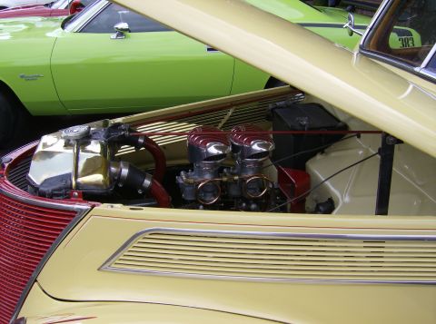 1970 Ford Ranchero - Close-up of a custom engine bay dual carburetors and a shiny radiator, with another vehicle visible behind it.