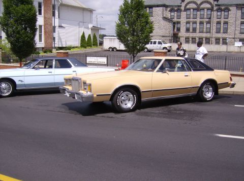 1970 Ford Ranchero - A tan 1977 Mercury Cougar XR-7 coupe is parked next to a light blue sedan.