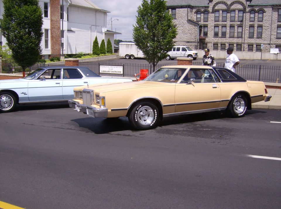 Tan 1977 Mercury Cougar XR-7 coupe with a black vinyl roof, seen from the front three-quarter angle