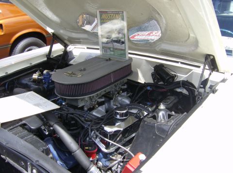 1970 Ford Ranchero - A magazine about Mustangs and Fords is displayed in the engine bay of a vehicle at a car show.