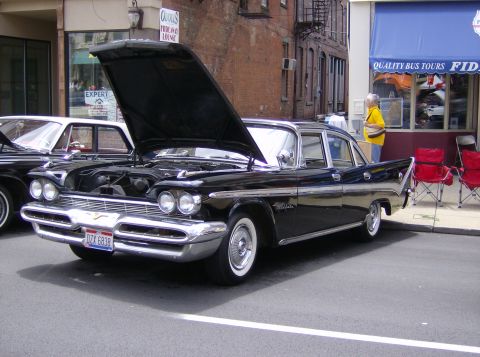 1970 Ford Ranchero - A classic black Plymouth sedan is displayed with its hood open, parked on a street next to another vehicle.