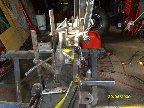 1989 Ford Bronco - A large tire and various pieces of machinery are visible in a cluttered garage setting, with a red gas can nearby.