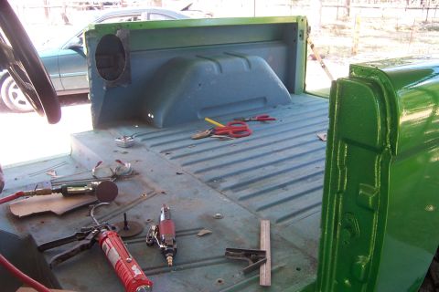 1976 Ford Bronco - Tools are laid out in the bed of a green vehicle, suggesting ongoing work or restoration.