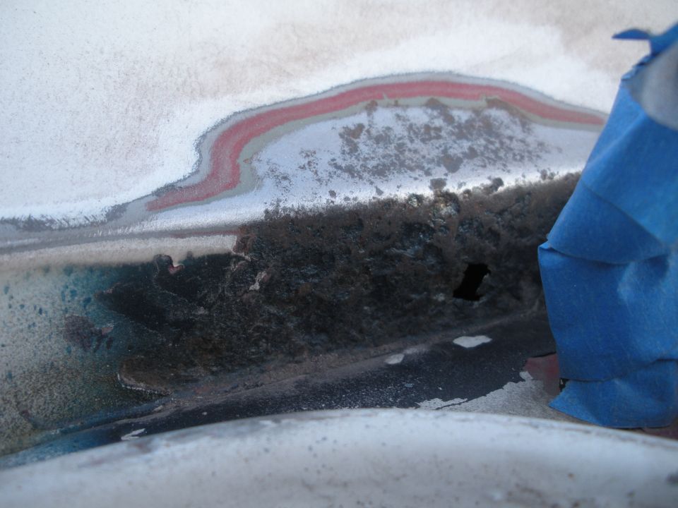 Close-up of rusted metal with blue painter's tape covering part of the area