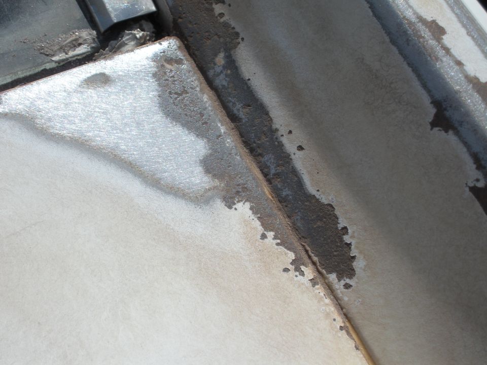 Close-up of rust and peeling paint on a car's body panel seam