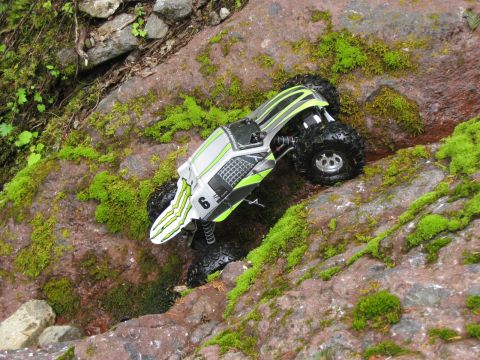 2010 Ford Pickup - A remote-controlled rock crawler navigates a challenging, moss-covered rocky terrain.