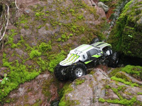 2010 Ford Pickup - A remote control monster truck traverses a rocky, moss-covered terrain with a small stream.