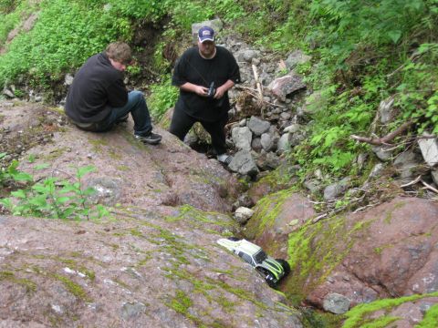 2010 Ford Pickup - Two people watch a remote control truck as it navigates a rocky, moss-covered stream bed.
