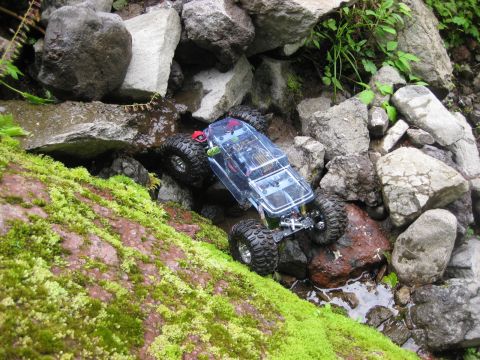 2010 Ford Pickup - Remote control rock crawler traversing a rocky, wet terrain with mossy rocks.