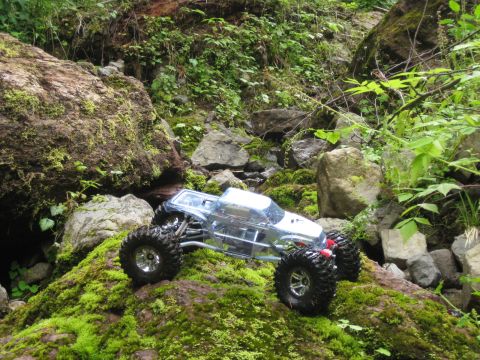2010 Ford Pickup - RC rock crawler truck navigating a rocky, moss-covered stream bed.