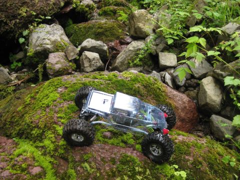 2010 Ford Pickup - A remote-controlled rock crawler navigates a rocky, moss-covered terrain.