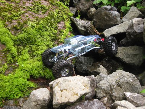 2010 Ford Pickup - A remote-controlled rock crawler navigates a challenging, rocky terrain covered in moss.
