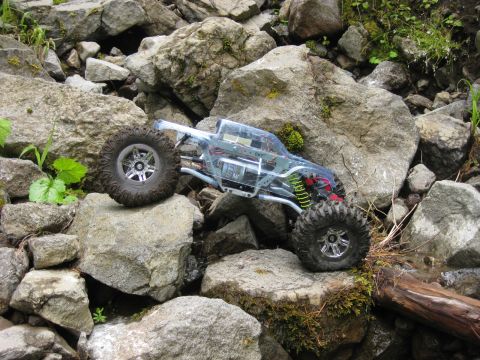 2010 Ford Pickup - A clear-bodied remote control rock crawler maneuvers over large rocks and mossy ground.