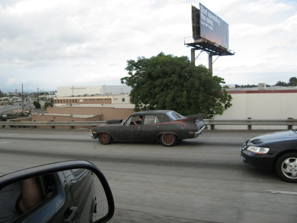 Dark sedan with hood scoop and spoiler on highway