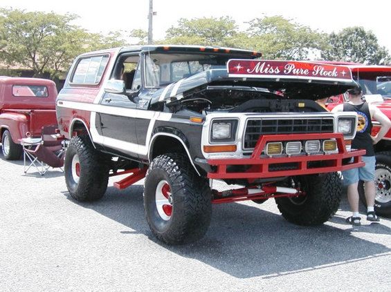Lifted black and white Ford Bronco with hood up, red tube bumper, Miss Pure Stock lettering